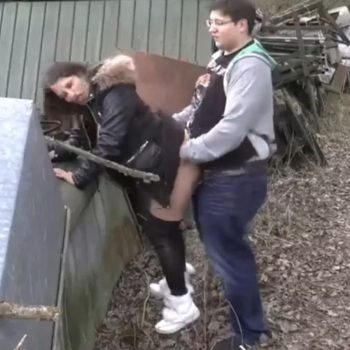 Outdoor doggy style by a garden shed, woman in a black jacket with fur collar and white sneakers